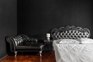 ein schwarzes Schlafzimmer mit einem Bett und einem Ledersessel in der Unterkunft Apartment Secret Place in Lwiw