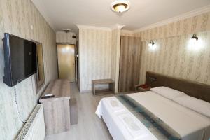 um quarto de hotel com uma cama e uma televisão de ecrã plano em Cagdas Hotel em Kusadasi