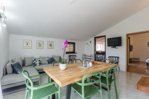 a living room with a wooden table and green chairs at Apartment Lungera in Pula