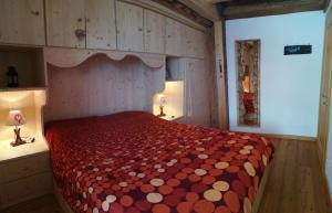 a bedroom with a bed with a red and white comforter at Tabià Fregona, Chalet Alpino con vista e stile tradizionale in Fregona