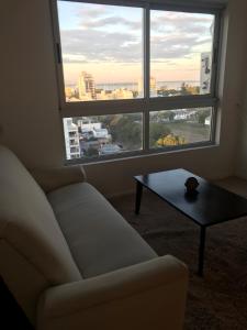 a living room with a couch and a table and a large window at Departamento 2 ambientes sobre el río Paraná Con Cochera in Corrientes