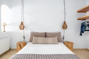 a bedroom with a white bed with two wooden stools at Ornos Blue in Ornos