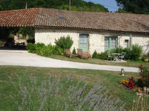 a stone house with a bench and flowers in front of it at La Maison de Maitre in Sainte-Livrade-sur-Lot