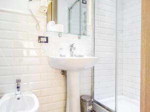 a white bathroom with a sink and a shower at Rome Central Inn in Rome