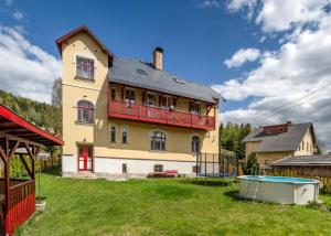 duży żółty dom z czerwonym balkonem w obiekcie Vila Josefina Jizerské hory w mieście Josefuv dul