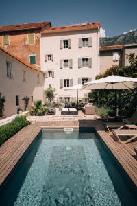 - une piscine en face d'un bâtiment avec un parasol dans l'établissement Palazzo Sbutega, à Kotor