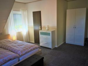 een slaapkamer met een bed, een dressoir en een raam bij Huus Störtebeker in Dornumersiel