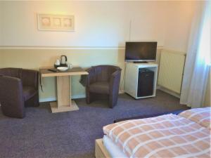ein Hotelzimmer mit einem Bett, einem Schreibtisch und einem TV in der Unterkunft Huus Störtebeker in Dornumersiel