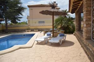 a patio with chairs and an umbrella next to a pool at Villa la Masia in Miami Platja