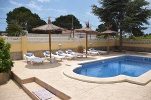 a swimming pool with chairs and umbrellas on a patio at Villa la Masia in Miami Platja
