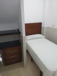 two beds in a small room with a desk and a bed at Pensión Juan Pedro in Roquetas de Mar