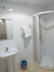 a white bathroom with a shower and a sink at Pensión Juan Pedro in Roquetas de Mar