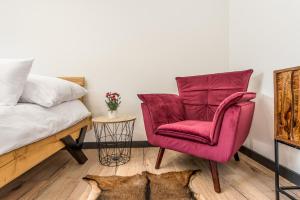 ein Schlafzimmer mit einem roten Stuhl neben einem Bett in der Unterkunft Sofia Boutique Hotel in Domaša Dobrá