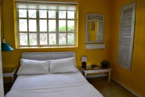 um quarto com uma cama com uma parede amarela e uma janela em Cabaña Villa del Viento em Paipa