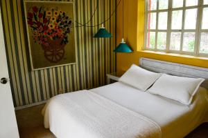 um quarto com uma cama branca e um quadro na parede em Cabaña Villa del Viento em Paipa