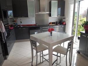 een witte keuken met een witte tafel en stoelen bij Villa de charme, séjour chez l'habitant in Andrésy