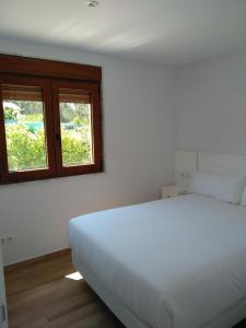 a bedroom with a white bed and two windows at Casa Da Fonte in Muxia