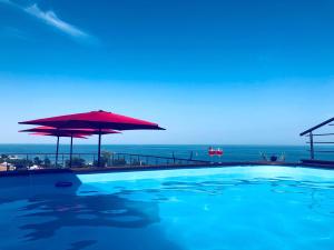 a swimming pool with a red umbrella and the ocean at For You in Odesa