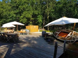a wooden deck with tables and umbrellas and a boat at Au Bois Flotté in Hourtin