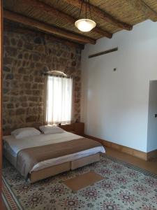 a bedroom with a bed and a brick wall at Domaine de Chouchene in Şaḩrat al Qashsh