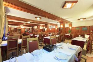 a dining room with white tables and chairs at Hôtel Soleil des Neiges in Le Sauze