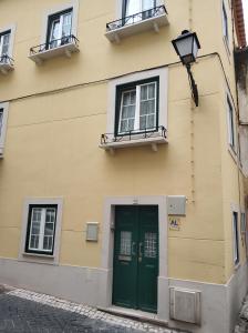 a building with a green door and two windows at Belo Apartment in Leiria