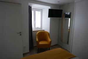 een kamer met een gele stoel en een spiegel bij Belo Apartment in Leiria