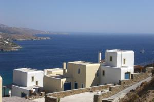 a group of white buildings on a cliff with the ocean at Monolithos Villas in Kipri