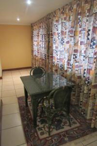 einen Tisch und einen Stuhl in einem Zimmer mit einem Vorhang in der Unterkunft Emafini Country Lodge in Mbabane
