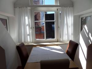 ein Esszimmer mit einem Tisch und einem Fenster in der Unterkunft Ferienwohnung über den Dächern in Lindau