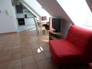 ein Wohnzimmer mit einem roten Sofa und einem TV in der Unterkunft Ferienwohnung über den Dächern in Lindau