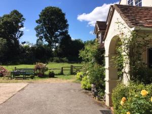 a house with a bench in a field with a fence at Bridge Cottage in Midhurst