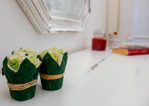 deux coupes de papier vert remplies de fleurs sur un comptoir dans l'établissement Casa don Luigi, à Cefalù