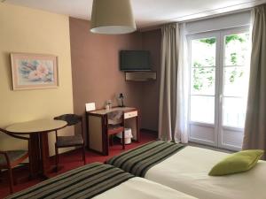 een hotelkamer met 2 bedden, een tafel en een raam bij Hôtel et Studios d'Orfeuil in Bourbonne-les-Bains