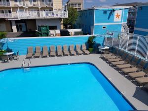 a large swimming pool with chairs and a building at Madison Beach Motel in Ocean City