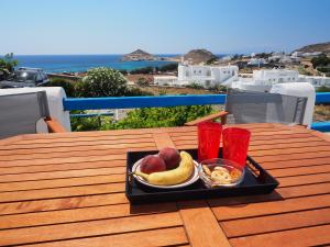 a tray of fruit on a table with two red cups at Chaniotis Studios in Kalafatis