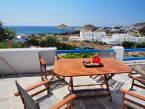 una mesa de madera y sillas en un patio con vistas al océano en Chaniotis Studios, en Kalafatis