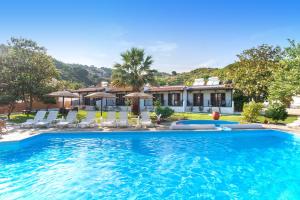 a swimming pool with chairs and a house at STRAWBERRY Skiathos in Agia Paraskevi