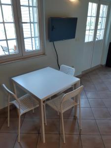 a white table and chairs in a room with a tv at Apartments Bianki in Slano