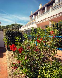 um arbusto com flores vermelhas em frente a um edifício em Fantastic 3-Bedroom Holiday Home including Tennis and Pool Near Golf Course em El Portil