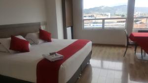 a bedroom with a large bed with red pillows and a window at Hotel Grand Premium Plaza in Pitalito
