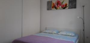 a bed in a white room with a purple blanket at Apartment Rita in Makarska