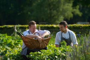 twee mannen in een tuin met een mand met planten bij Romantik Hotel Jagdhaus Eiden am See in Bad Zwischenahn