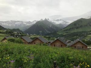 un groupe de maisons sur une colline avec des montagnes en arrière-plan dans l'établissement appartement au pied des pistes, à La Chal