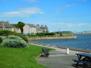 ロジーマスにあるWELCOMEHOUSE close to east beach, shops, restaurants and RAF baseの水の横に座る公園のベンチ
