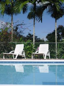 two white chairs sitting next to a swimming pool at Tamarind Great House in Oracabessa