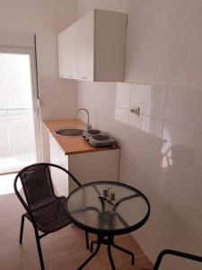 a small kitchen with a glass table and a chair at Apartmani Neo in Sutomore