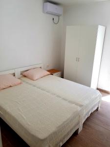 a bedroom with a white bed with pink pillows at Apartmani Neo in Sutomore