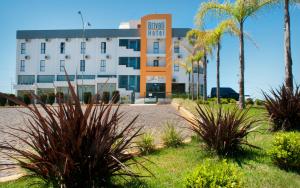 a hotel with palm trees in front of it at Brivali Hotel e Eventos in Caçador