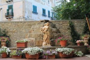 a statue in front of a stone wall with pots of flowers at Hotel Ristorante Mariano in Stigliano